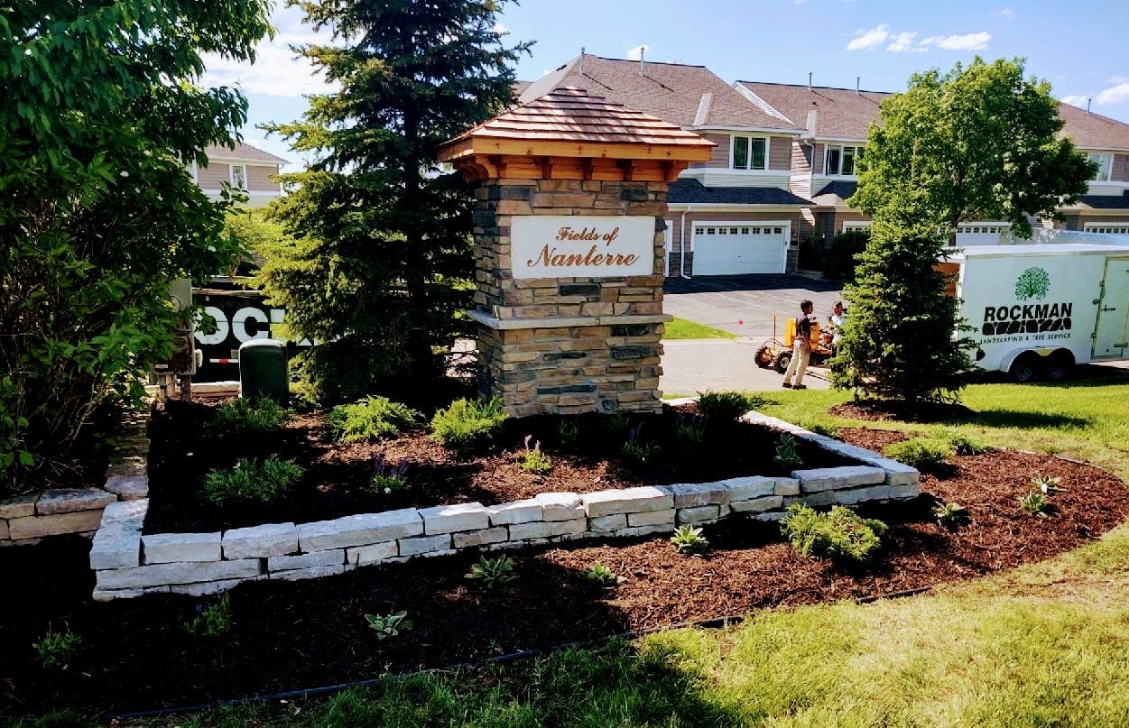 Stone HOA entrance sign with landscaped beds